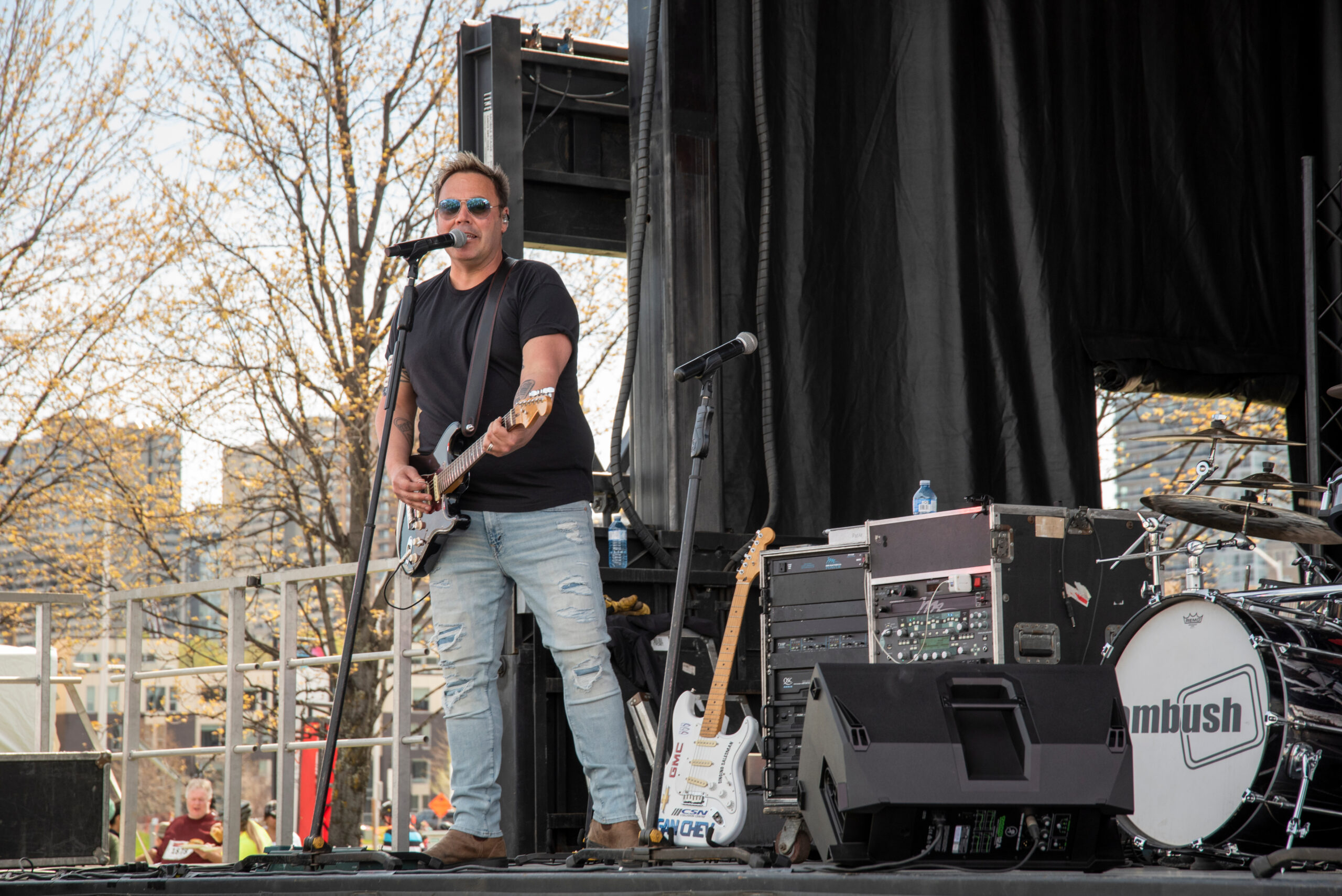 Musician on stage singing and playing electric guitar.